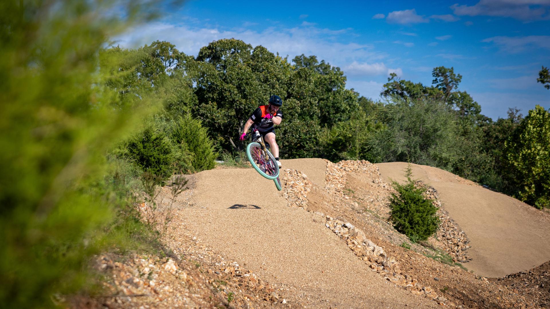 Rider jumping over roller on downhill flow line