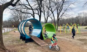 Kids riding bikes through elevated tunnels in bicycle playground