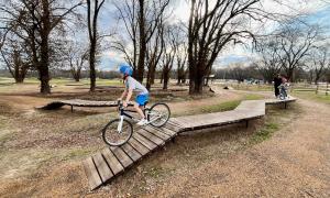 Kids on bikes riding wooden features in bike skills course